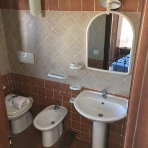 een badkamer met een wastafel, een toilet en een spiegel bij Hotel Bed Sandalia in Badesi