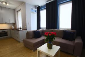 ein Wohnzimmer mit einem Sofa und einem Tisch mit Blumen in der Unterkunft Apartamenty Chwytowo 14 in Bydgoszcz