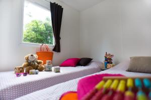 a bedroom with two beds and a teddy bear on the bed at Camping Officiel Siblu Le Bois Dormant in Saint-Jean-de-Monts