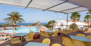 a patio with tables and chairs and a swimming pool at Sun Club El Dorado - All Inclusive in Llucmajor