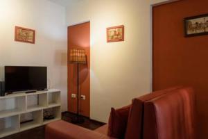 Sala de estar con puerta, TV y silla en Apartamento Pueyrredón en Córdoba