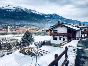 a house in the snow with mountains in the background at Chèvres à Cheval - Apartment in Aosta