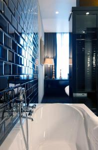 een badkamer met een bad en een blauwe tegelmuur bij Hotel Les Nuits in Antwerpen