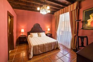 a bedroom with a bed in a room with red walls at Hotel Emblemático San Marcos in Icod de los Vinos