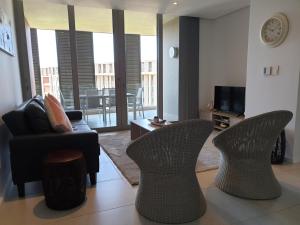 ein Wohnzimmer mit einem Sofa, Stühlen und einem TV in der Unterkunft Ocean Dunes T428 in Durban