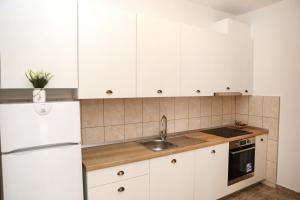 a kitchen with white cabinets and a sink at Apartman Aurora in Solde
