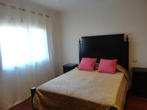 a bedroom with a bed with two pink pillows at Beach front sunset apartment in Apúlia
