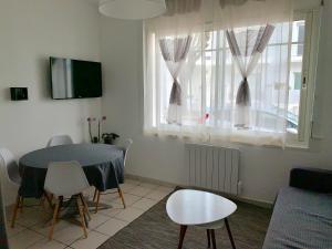 a living room with a table and chairs and a window at Appartement des Tilleuls RDC in Royan