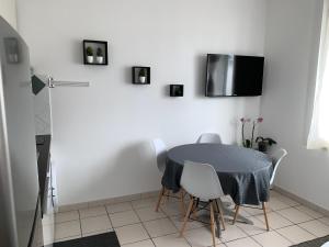 a dining room with a table and a tv on the wall at Appartement des Tilleuls RDC in Royan