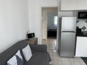 a living room with a couch and a refrigerator at Appartement des Tilleuls RDC in Royan