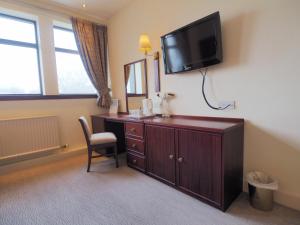 Habitación de hotel con escritorio y TV en la pared en Caladh Inn, en Stornoway