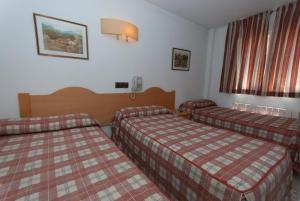 a hotel room with two beds and a window at Hostal Goyma II in San Fernando de Henares