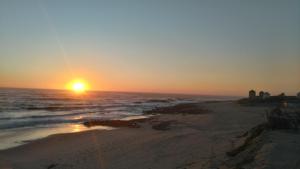 una puesta de sol en una playa con el océano en Beach front sunset apartment, en Apúlia