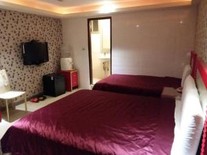 ein Hotelzimmer mit 2 Betten und einem TV in der Unterkunft Meets Happy Hotel in Yonghe