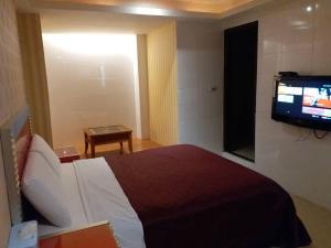 ein Hotelzimmer mit einem Bett und einem Flachbild-TV in der Unterkunft Meets Happy Hotel in Yonghe