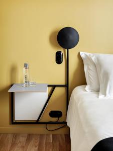 a bed with a black lamp next to a side table at New Hotel Le Voltaire in Paris