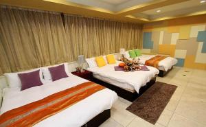 a hotel room with three beds in a room at Simplicity Sojourn Hualien in Hualien City