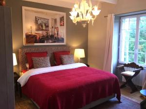 a bedroom with a red bed and a chandelier at La Colline des Renards Chambres in Locmaria-Berrien