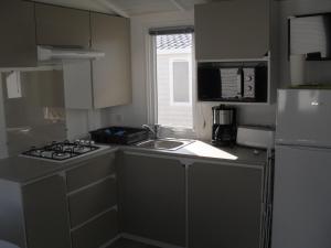 a kitchen with a stove and a sink and a refrigerator at Camping de la Mer in Camiers