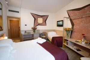 a hotel room with two beds and a mirror at iH Hotels Milano St. John in Sesto San Giovanni