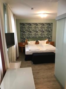 a bedroom with a large bed and a tv at Flair Hotel zum Storchen in Bad Windsheim