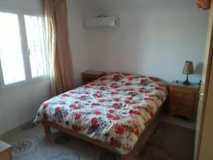 a bedroom with a bed with a floral comforter and a window at Beltaief Residence in Houmt Souk