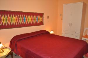 a bedroom with a red bed and a window at Casa Bianca Del Centro in San Vito lo Capo