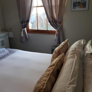 1 dormitorio con cama con almohadas y ventana en Waterfront Hotel, en Deal