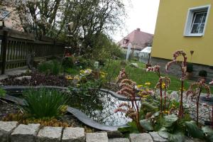 un giardino con laghetto e fiori in un cortile di Ferienwohnung Dieter Popp a Münchberg