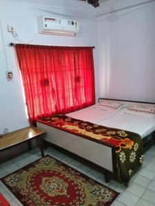 a bedroom with two beds and a red curtain at Chaiti Lodge - Santiniketan Bolpur in Bolpur