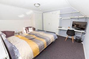 Schlafzimmer mit einem Bett, einem Schreibtisch und einem TV in der Unterkunft Bed & Breakfast Kroese in Oldenzaal