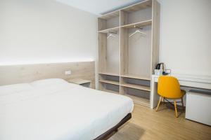 a bedroom with a white bed and a yellow chair at Solesperit in Lloret de Mar
