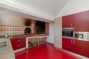 a kitchen with red cabinets and a brick oven at OurMadeira - Villa do Mar III, secluded in Arco da Calheta