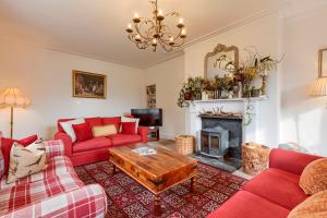 a living room with red couches and a fireplace at Ardveich House, large Scottish estate home with loch & hill views in Lochearnhead