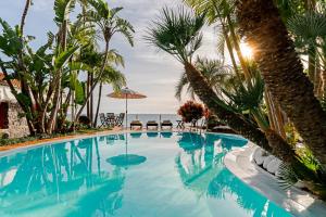 una piscina con palmeras y el océano en OurMadeira - Villa do Mar I, secluded, en Arco da Calheta