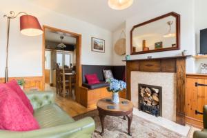 a living room with a fireplace and a green couch at Fergies Canal Side Cottage in Warwick