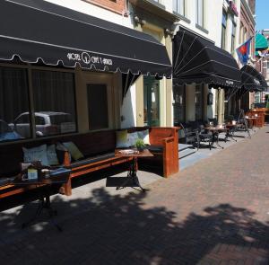 een straat met tafels en parasols op een stoep bij Hotel 't Anker in Leeuwarden