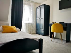 a bedroom with a bed and a desk and a yellow chair at Hotel Tara in Kielce