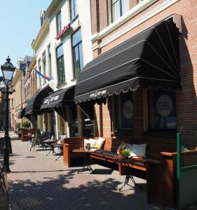 a sidewalk with tables and umbrellas on a street at Hotel 't Anker in Leeuwarden