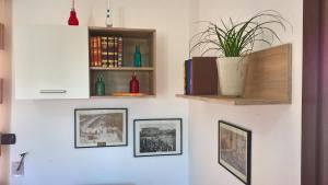 eine weiße Wand mit Bildern und einer Pflanze darauf in der Unterkunft Le more Holiday Home in Casarano