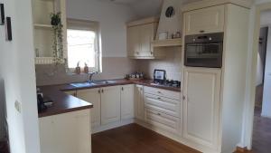 a kitchen with white cabinets and a sink at Vakantiehuis de wilgenhof in Wetering