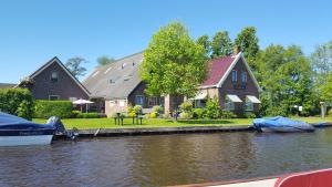 a house with a boat parked in front of a river at Vakantiehuis de wilgenhof in Wetering