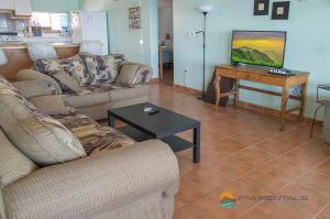 a living room with couches and a flat screen tv at Casa Pelicano in Puerto Peñasco