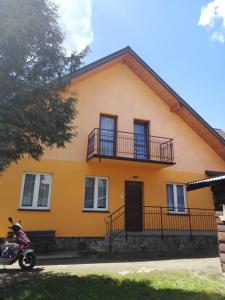 a yellow house with a scooter parked in front of it at NOCLEGI U STASI in Cisna