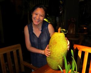 a woman is holding a large yellow pear on a table at Pura Vida Hotel in Alajuela City