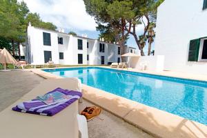 una piscina con un sillón junto a un edificio en Apartamentos Cala Blanca, en Cala Blanca