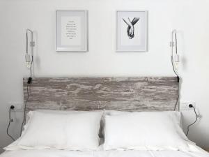 1 cama con 2 almohadas blancas y 2 cuadros en la pared en Apartamento Homies Córdoba en Córdoba