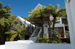 een wit gebouw met palmbomen ervoor bij te Whare -Lake Tarawera tree-top nest in Lake Tarawera