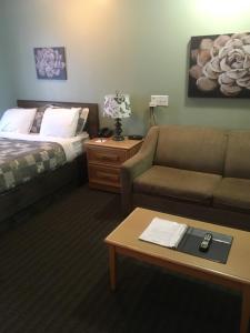 a hotel room with a couch and a bed and a table at Restland Motel in Clarenville