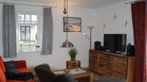 a living room with a couch and a tv on a dresser at Ferienwohnung Baltic Sea in Börgerende-Rethwisch